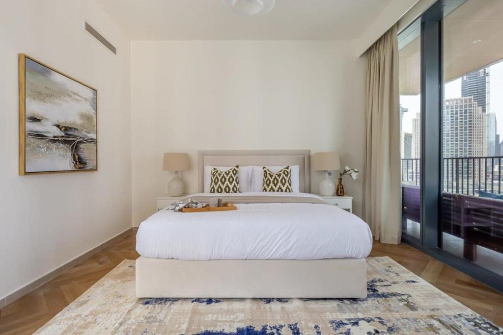 a white bedroom with a large bed and a large window at Frank Porter - BLVD Heights T1 in Dubai