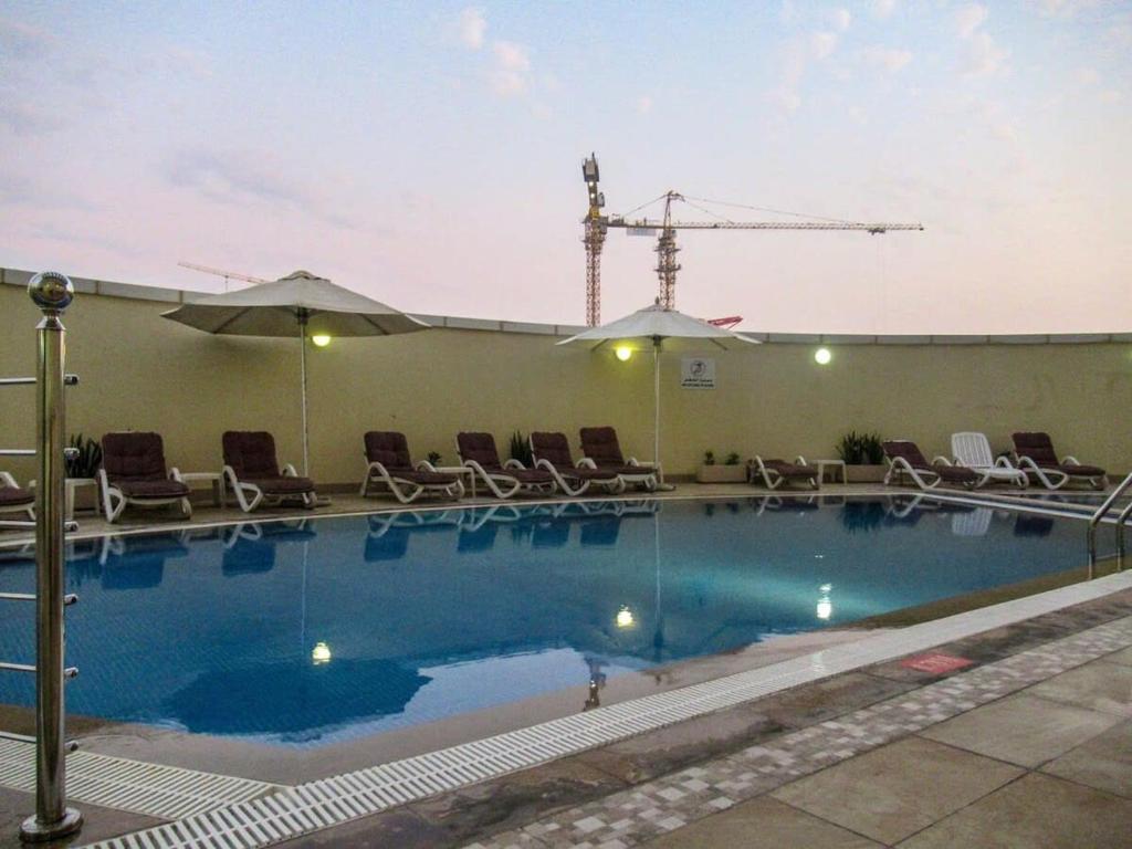 a swimming pool with chairs and a crane in the background at Frank Porter - Goldcrest Executive in Dubai