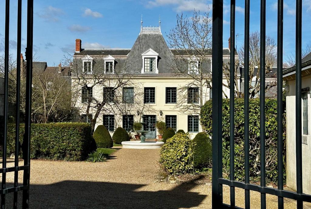 an open gate to a large white house at Le Vieux Manoir in Amboise