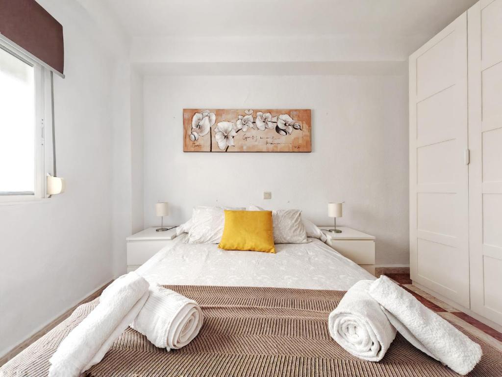 a white bedroom with a bed with towels on the floor at Gran apartamento en el Centro Histórico in Málaga