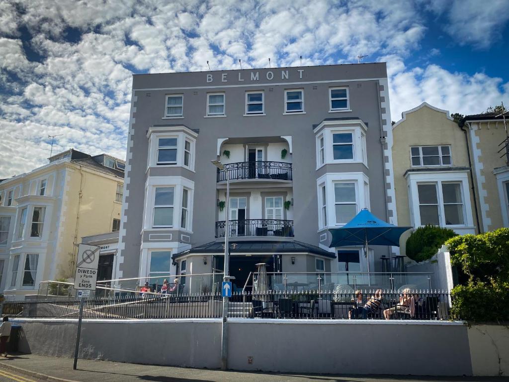 un gran edificio con gente sentada fuera de él en Belmont Llandudno en Llandudno