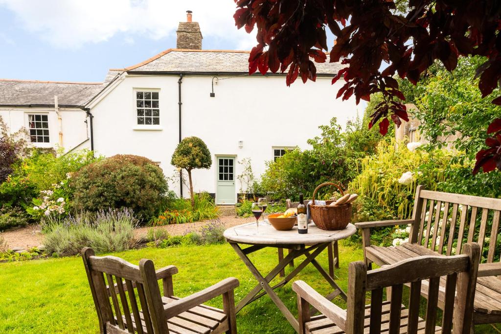 een tuin met een tafel en twee stoelen en een wit huis bij Blackbird Cottage in Bideford