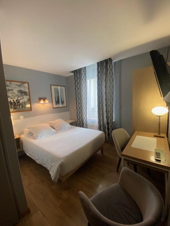 a bedroom with a bed and a desk and a chair at Hotel Le Pelican in Charleville-Mézières