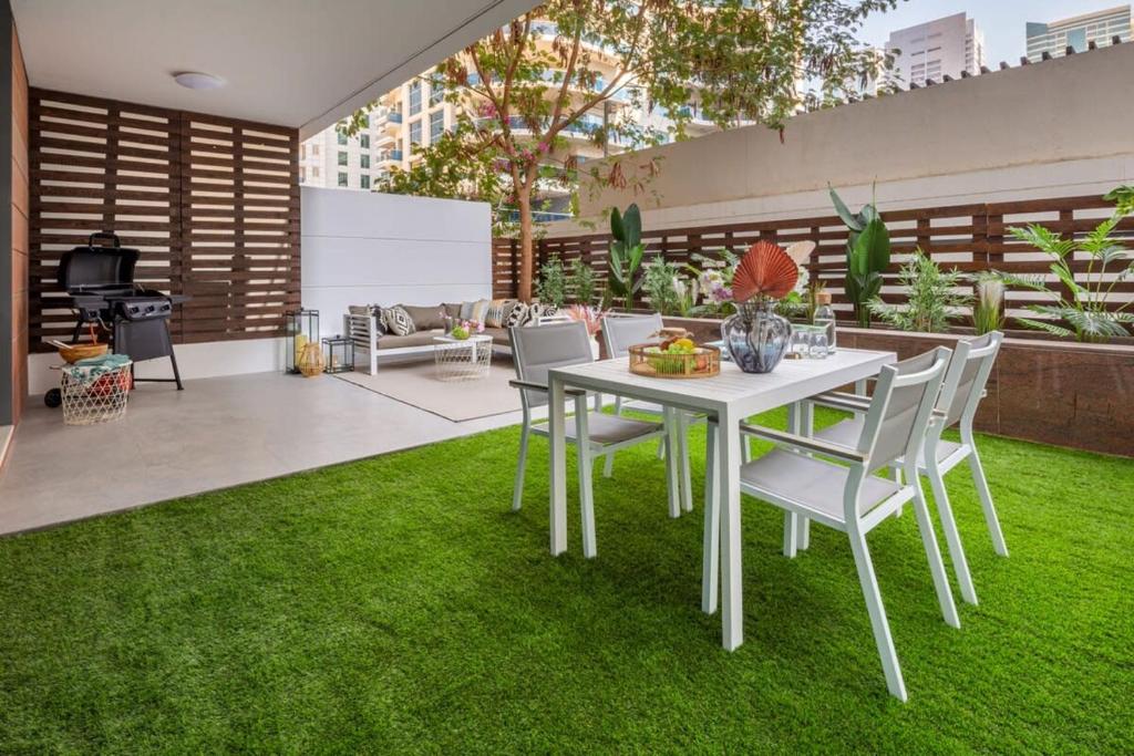 a patio with a white table and chairs on grass at Frank Porter - Azure in Dubai