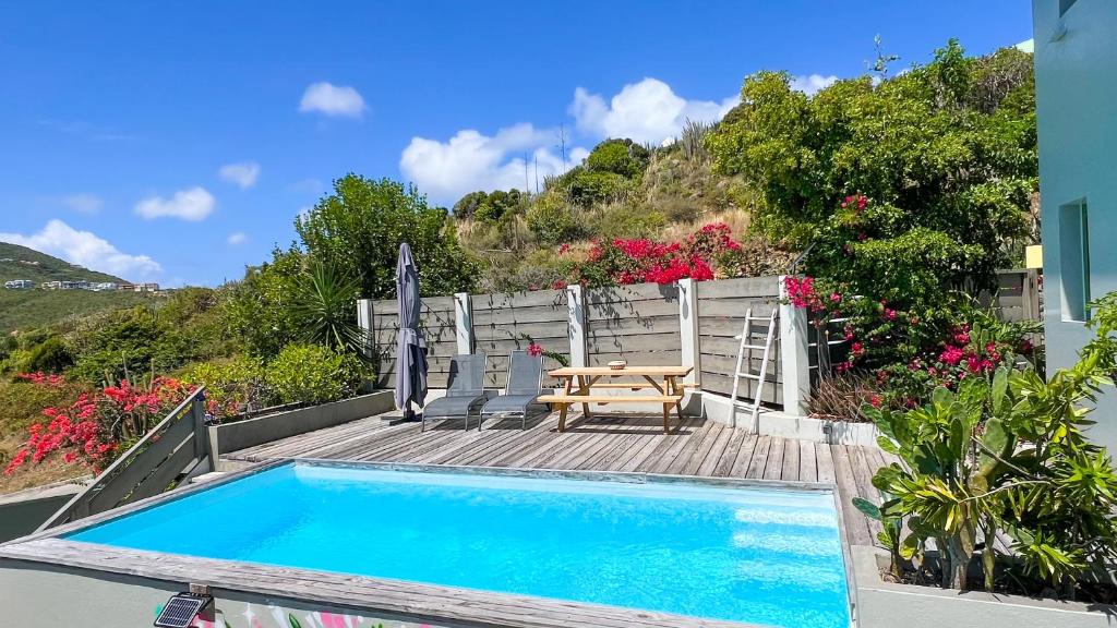 a swimming pool with a table and a wooden deck at VILLA MAGIC in Oyster Pond