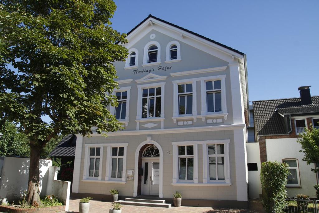 博爾庫姆的住宿－Gästehaus Teerlings Hafen，前面有一棵树的白色房子