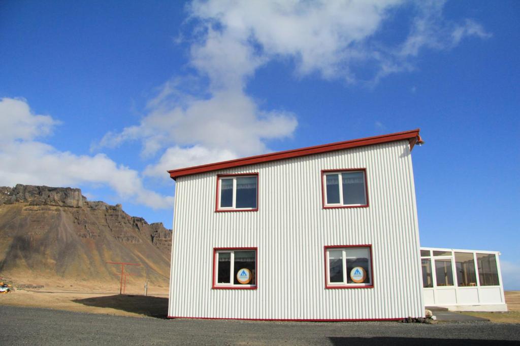 a white building with a mountain in the background at Vagnsstadir in Borgarhöfn