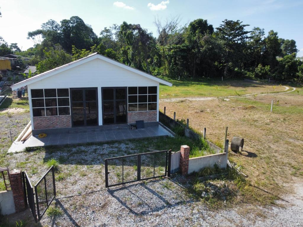 une petite maison avec une clôture dans un champ dans l'établissement Qimmy Riverside Guesthouse, à Kuala Terengganu