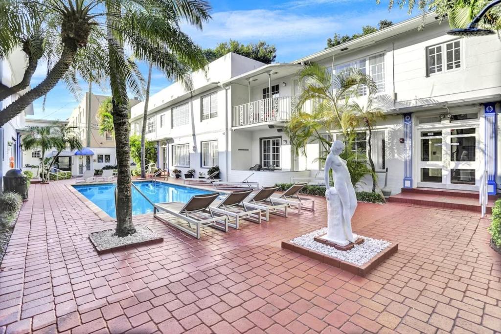 a house with a swimming pool and palm trees at Courtyard Apartments Part of the Oasis Casita Collection in Miami Beach