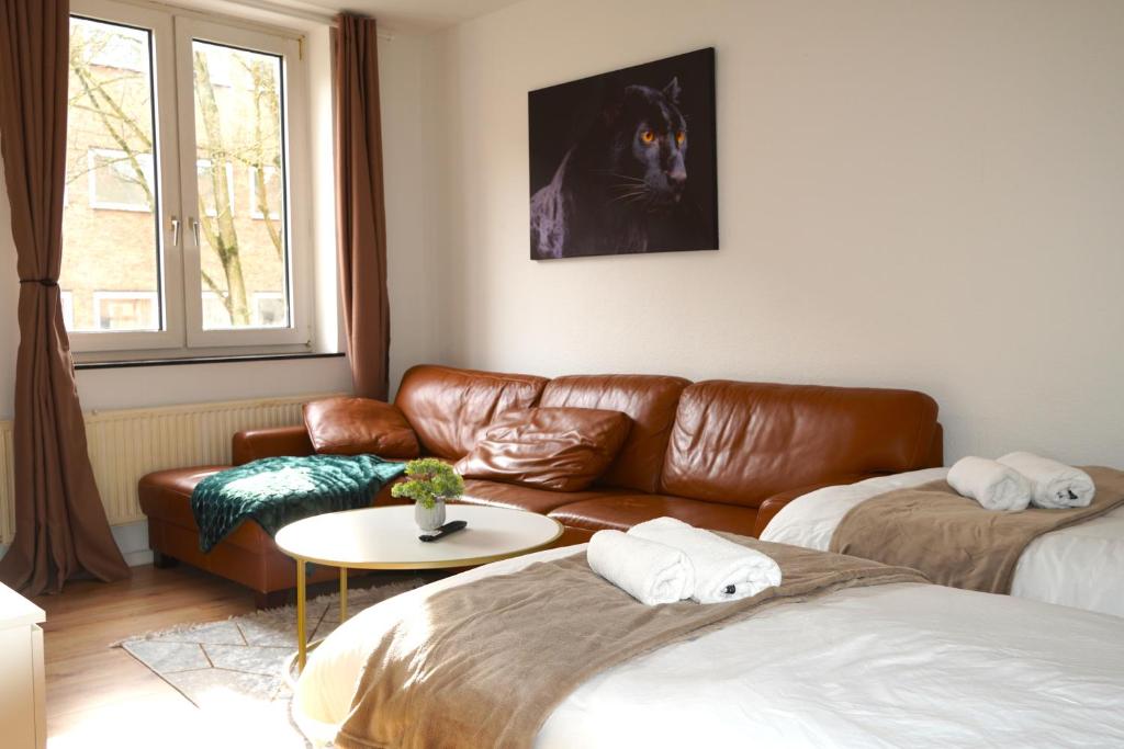 ein Wohnzimmer mit einem Ledersofa und einem Tisch in der Unterkunft Timeless Apartment II Bremen-Neustadt in Bremen