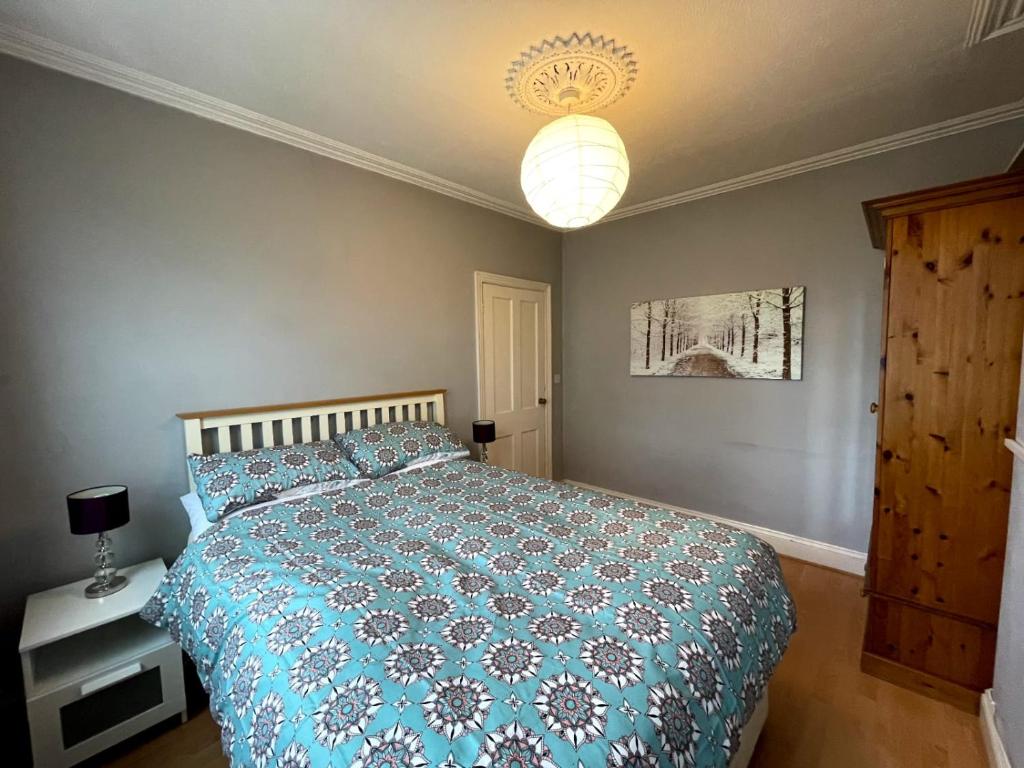 a bedroom with a bed with a blue comforter at The Claude House in Bath