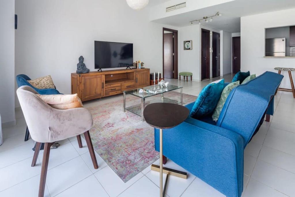 a living room with a blue couch and a tv at Frank Porter - Marina Tower in Dubai