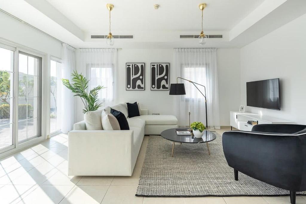 Sala de estar blanca con sofá blanco y mesa en Frank Porter - District 16, JVC, en Dubái