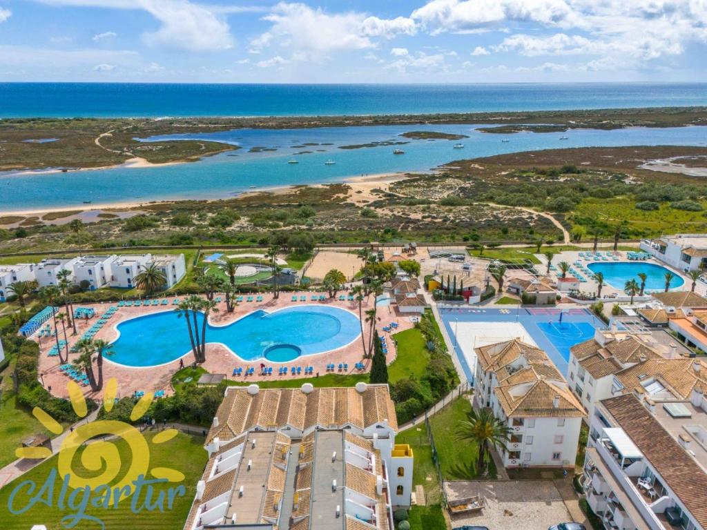 an aerial view of a resort with a pool and the ocean at Sunny Golden 1BDR Apartment w Beach & Pool Access Included in Cabanas de Tavira