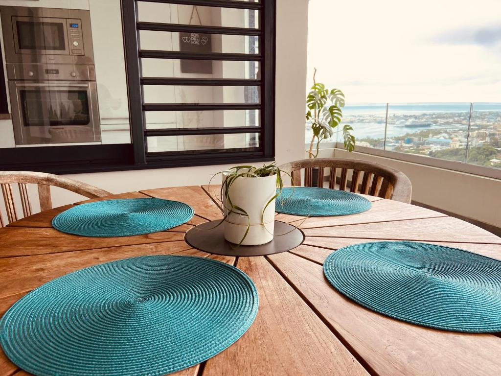 une table en bois avec quatre plaques bleues dessus dans l'établissement Meherio - Bel Appartement vue mer à TAHITI, à Papeete