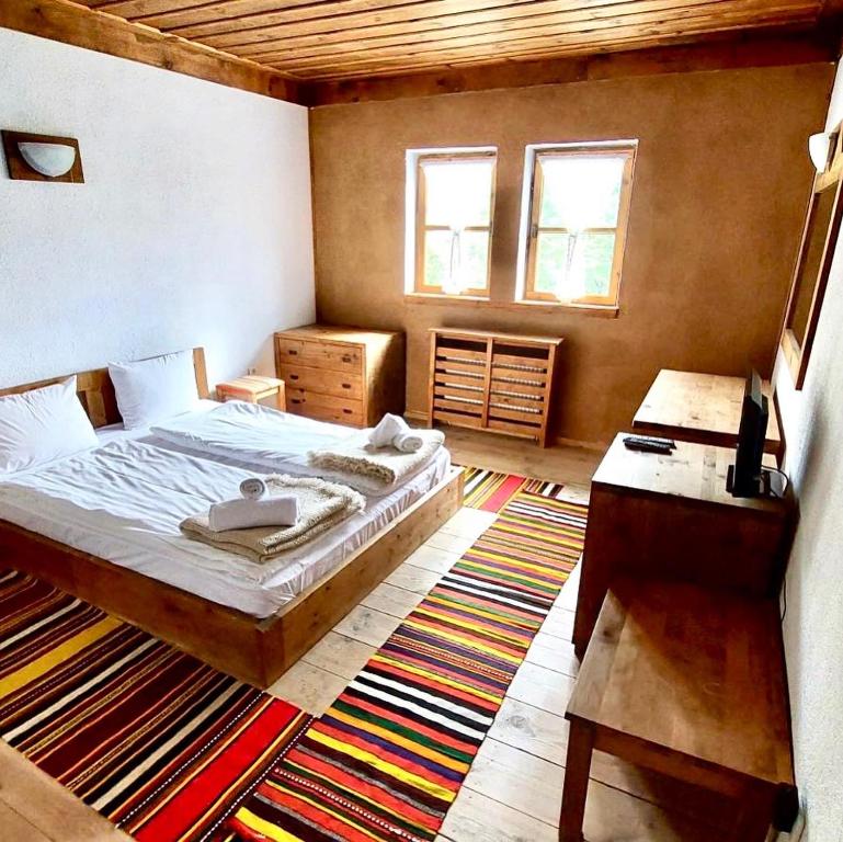 a bedroom with a bed and a desk in it at Family Hotel Byalata Kashta in Kovachevitsa