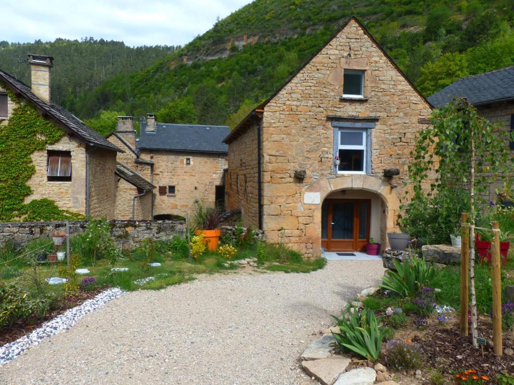 a stone house with a driveway in front of a mountain at Gîte le Nid du Colibri - 12 pers in Brenoux