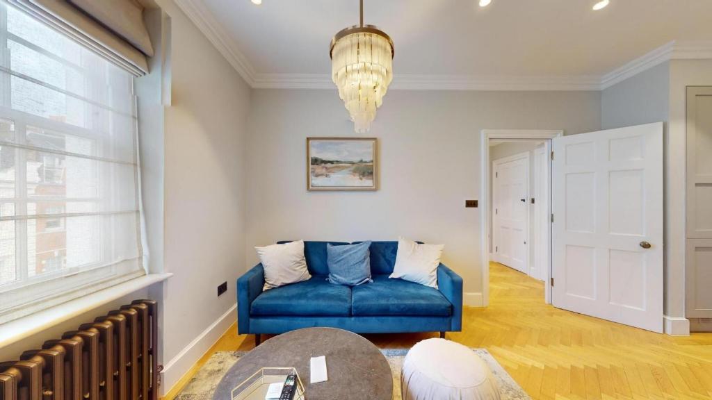 a living room with a blue couch and a table at The Wimpole IX - 1 bed flat in London