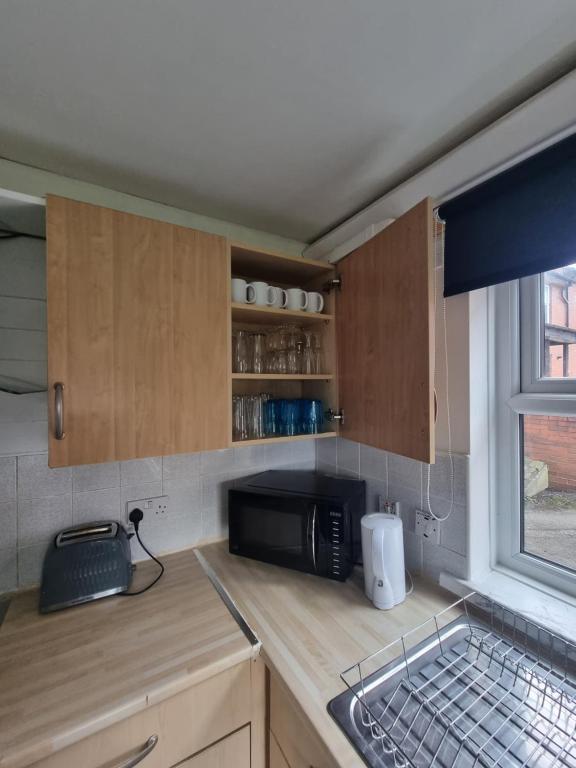 um balcão de cozinha com um micro-ondas e uma janela em 2 Bedroom Cozy Chambers with free parking em Leeds