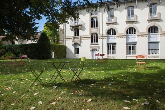 two chairs and a table in front of a building at Hotels &amp; Résidences - Les Thermes in Luxeuil-les-Bains