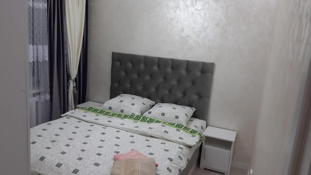 1 dormitorio con cama con cabecero gris y almohadas en уютная 3 комнатная в центре города, en Shymkent