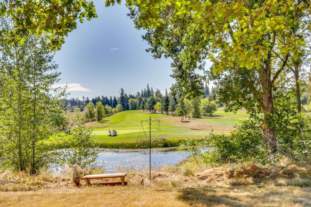un banco de parque junto a un estanque con un campo de golf en Chehalis Getaway with Golf Course View and Fire Pit!, en Chehalis