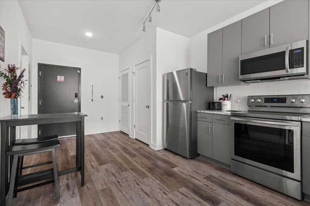 a kitchen with stainless steel appliances and wooden floors at New Building Downtown Atlanta Condo in Atlanta
