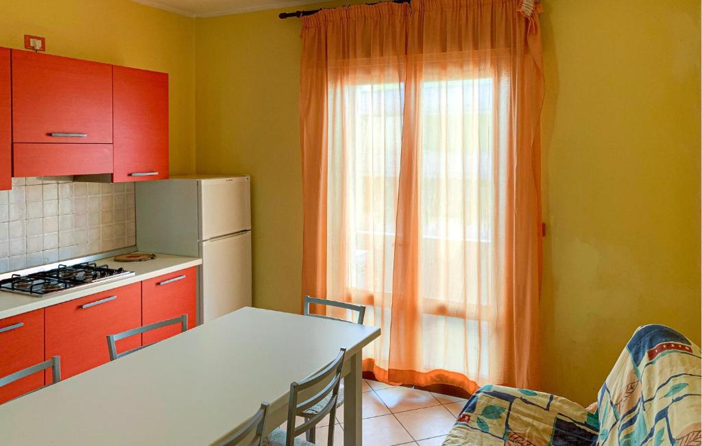 une cuisine avec des placards rouges, une table et une fenêtre dans l'établissement Mara 12, à Rosolina Mare