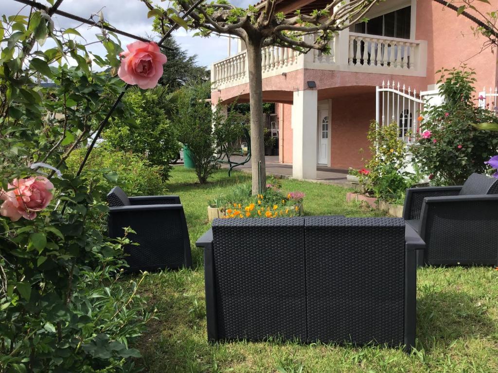- un jardin avec des chaises et des fleurs devant une maison dans l'établissement Appartement Vals les bains, à Vals-les-Bains