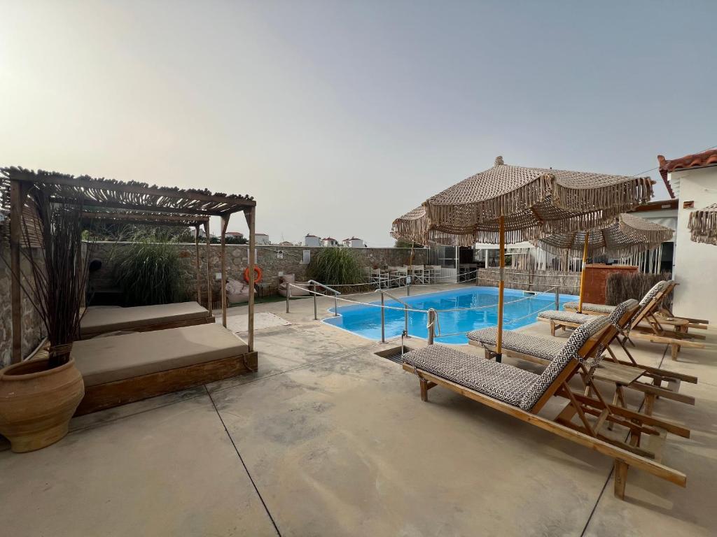 a pool with chairs and umbrellas on a patio at koukounari 3 superior rooms in Skala