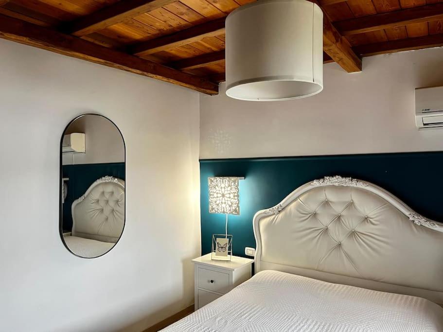 een slaapkamer met een wit bed en een spiegel bij Accogliente Trilocale Vista Lago in Anguillara Sabazia