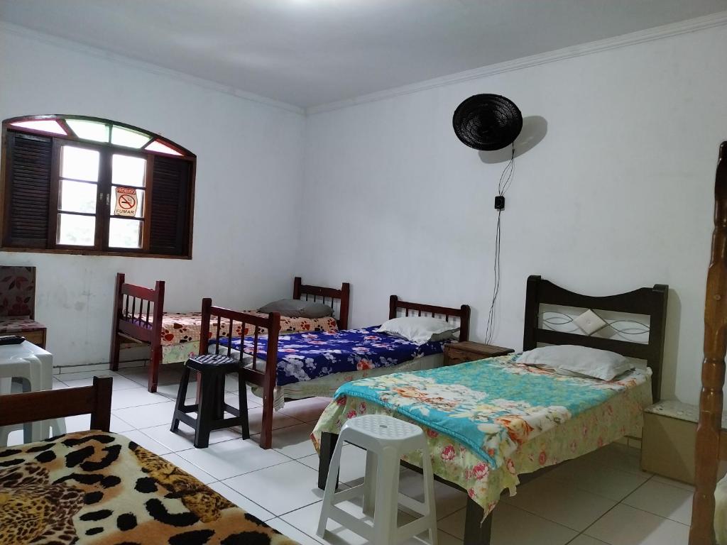 a bedroom with two beds and a table and chairs at POUSADA PERLLA's Pindamonhangaba in Pindamonhangaba