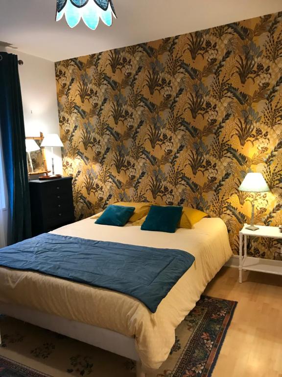 um quarto com uma cama com almofadas azuis e papel de parede em Chambre d’hôte Lyons la foret em Lyons-la-Forêt