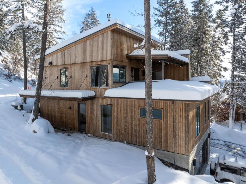 a wooden house in the woods in the snow at Whitefish Suncrest Charm- Newly Build Modern Townhouse w Pool Table andPet Friendly! in Whitefish
