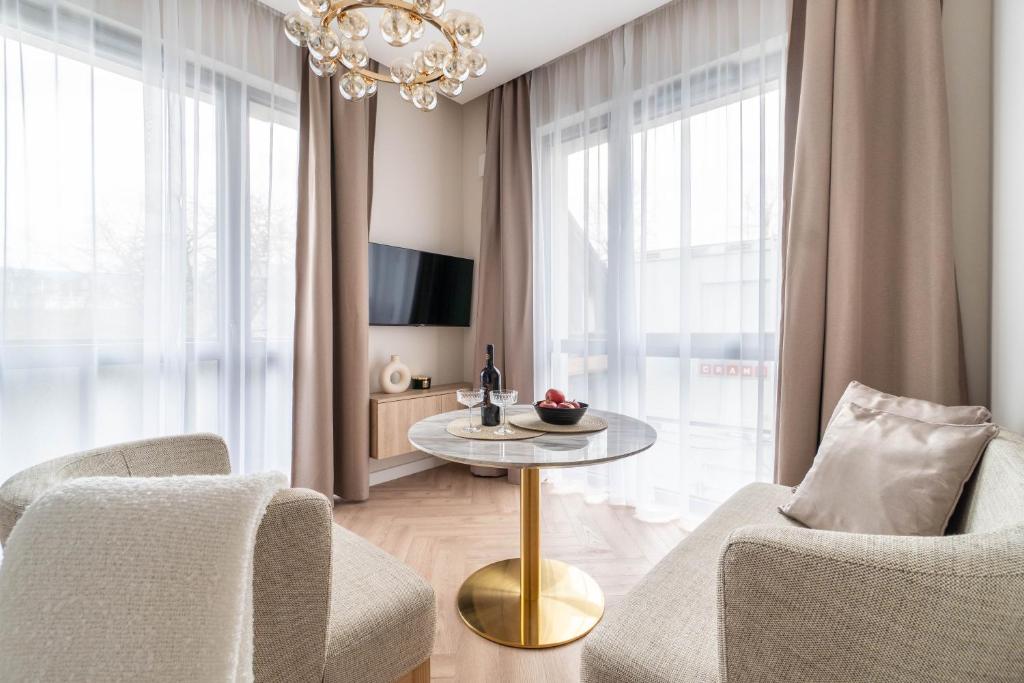 uma sala de estar com um lustre e uma mesa e cadeiras em Golden Apartment Paupys em Vilnius