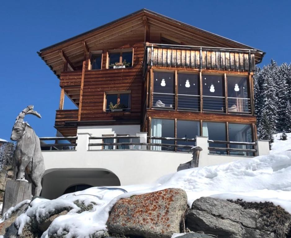 una casa de madera en la nieve con una estatua de cabra delante en Chalet Sonnenschein en Davos