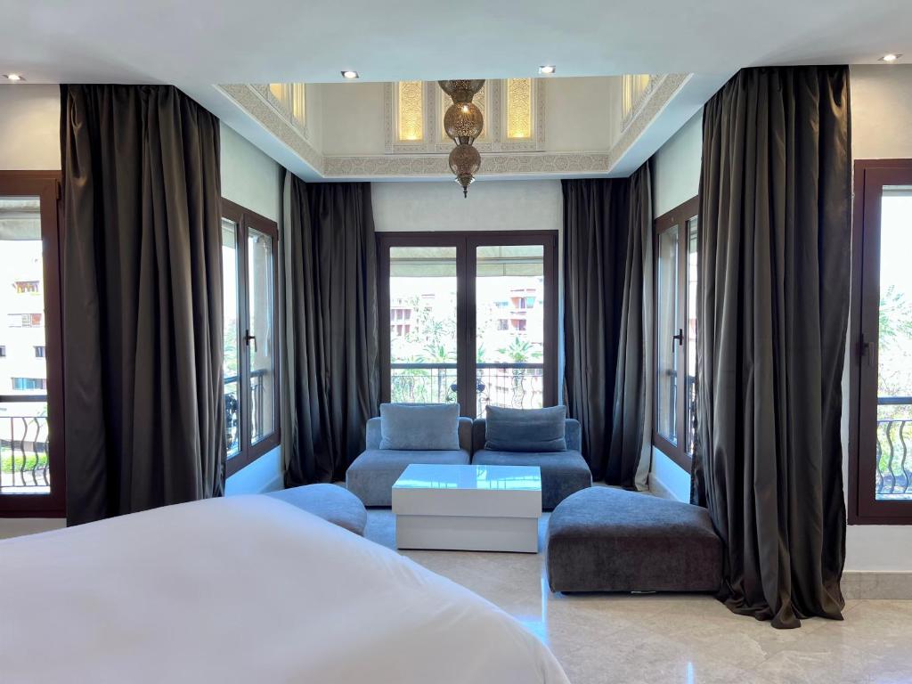 Superbe appartement de luxe a l'hivernage marrakech في مراكش: غرفة نوم بسرير واريكة ونوافذ