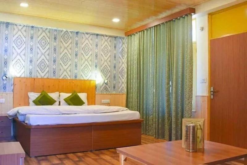 a bedroom with a large bed and a table at Hotel Seraj International , Aleo Hill View in Manāli
