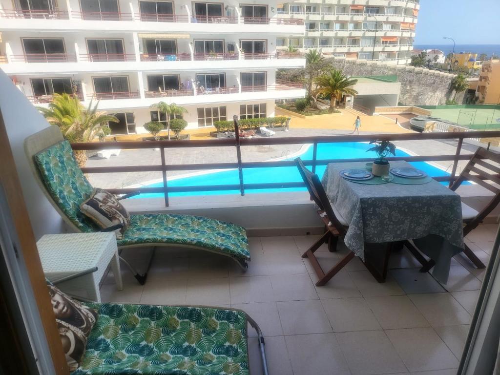 balcón con mesa, sillas y piscina en Apartamento Sol & Arena, en Puerto de Santiago