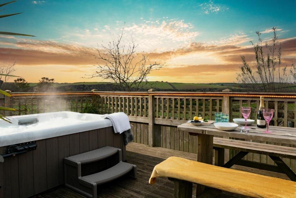 bañera en una terraza con mesa y copas de vino en Lily Pad Cottage with hot tub, en Padstow