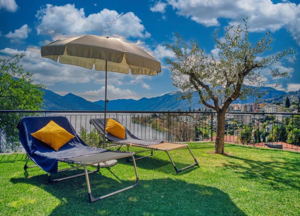two chairs and an umbrella on a lawn at Casa Alla Roccabella in Minusio