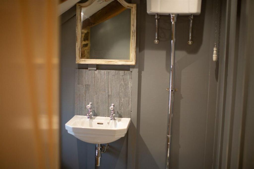 a bathroom with a sink and a mirror at The Grooms Cottage in Longwitton
