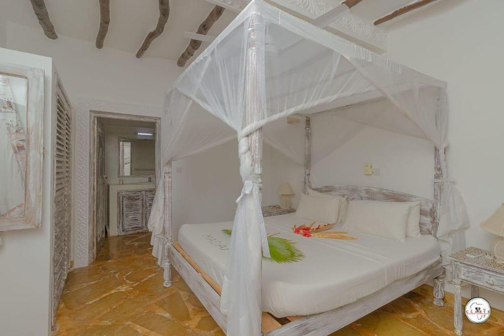 um quarto com uma cama de dossel branca em Kenya Residence Watamu em Watamu