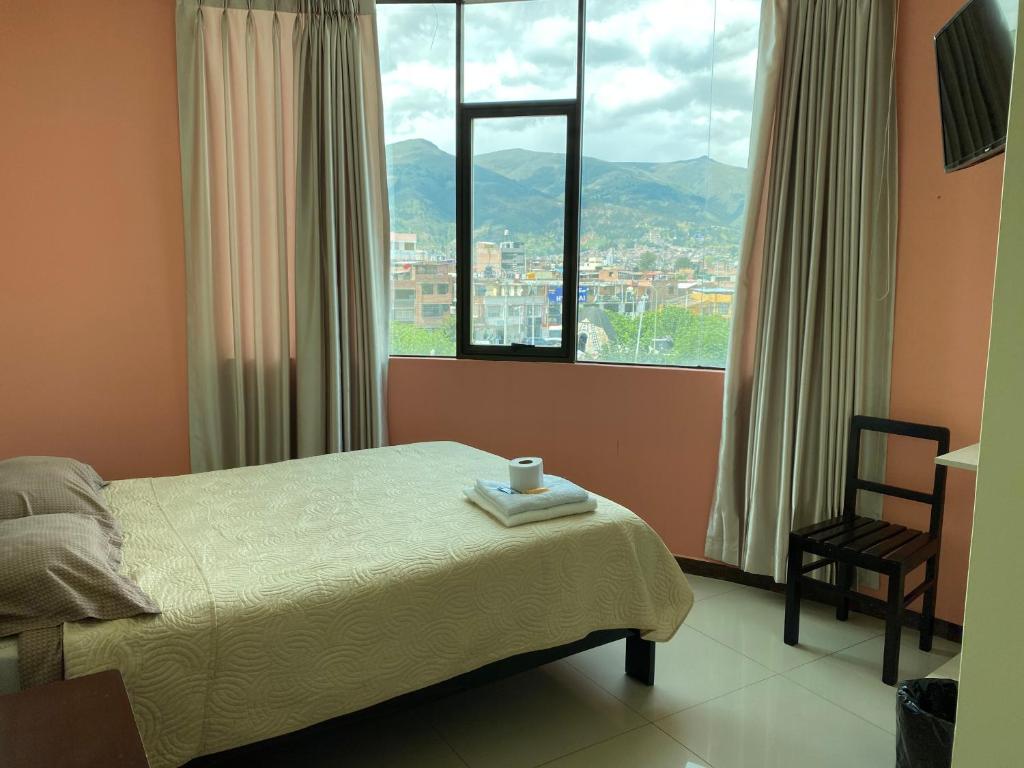 a bedroom with a bed and a chair and a window at Rooms MD y FS in Huancayo