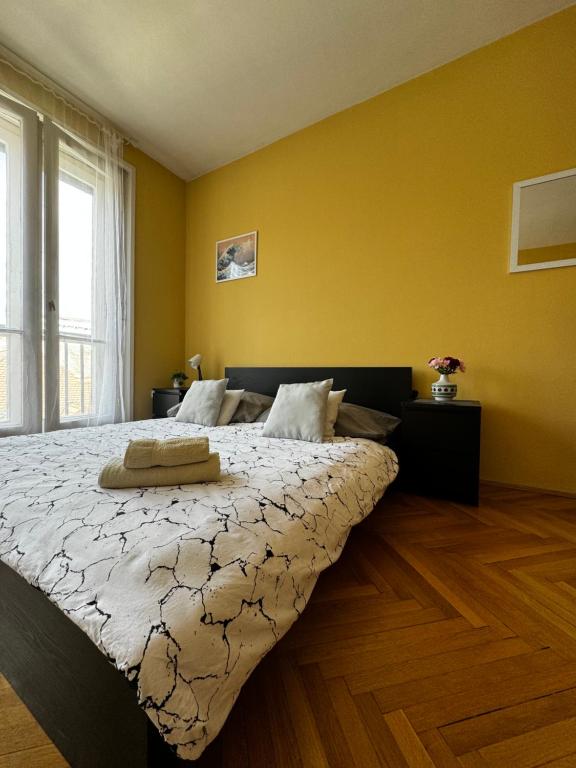 a bedroom with a large bed in a yellow wall at Extralarge Queen Room in the Heart of Bratislava with Terrace in Bratislava