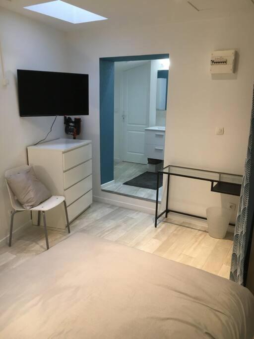 een slaapkamer met een bed en een televisie en een spiegel bij Suite atypique de qualité in Orsay