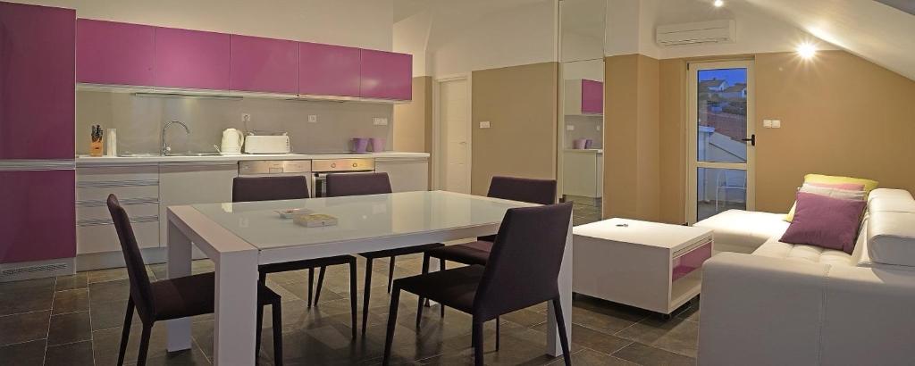 eine Küche und ein Wohnzimmer mit einem weißen Tisch und Stühlen in der Unterkunft Villa Via with appartments Lemon,Olive,Lavender in Maslinica