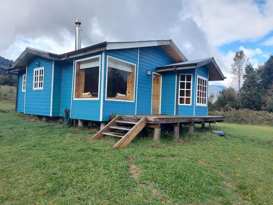 una casa blu seduta in cima a un campo di Cabaña Queltehue Cochamó a Cochamó