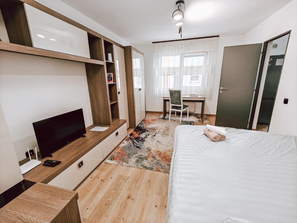 een slaapkamer met een bed, een tv en een bureau bij Charming City Hideout in Cluj-Napoca