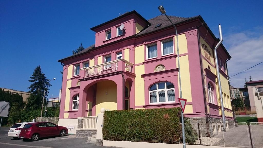 a pink building with a car parked in front of it at Pension Viola in Domažlice